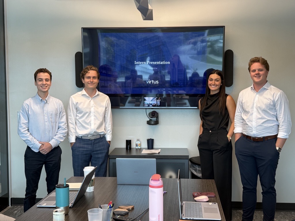 Four interns beside a screen displaying their Virtus intern presentation
